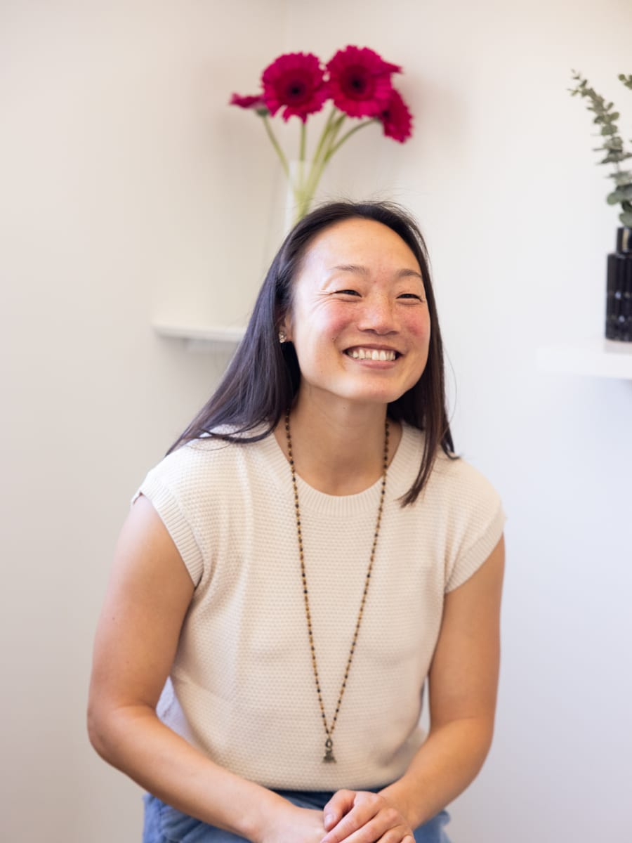 Nina Jung, licensed acupuncturist, smiling warmly in her clinic.