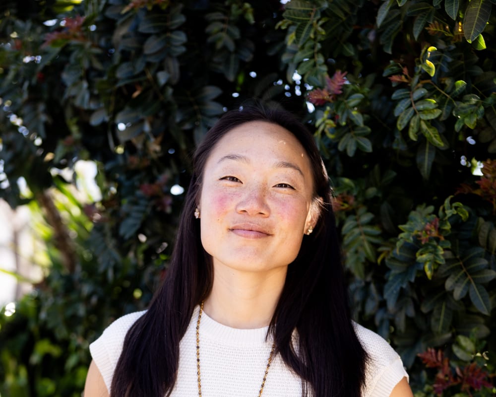 Nina Jung standing among greenery, calm and grounded.