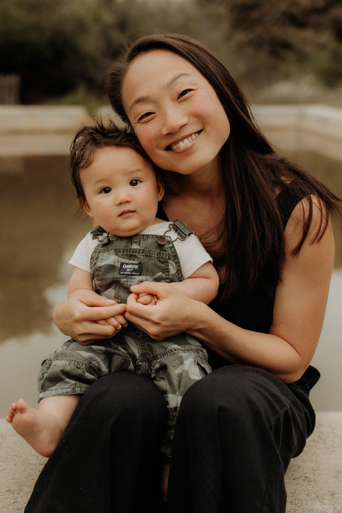Nina Jung outdoors holding her young child, warm and at ease.